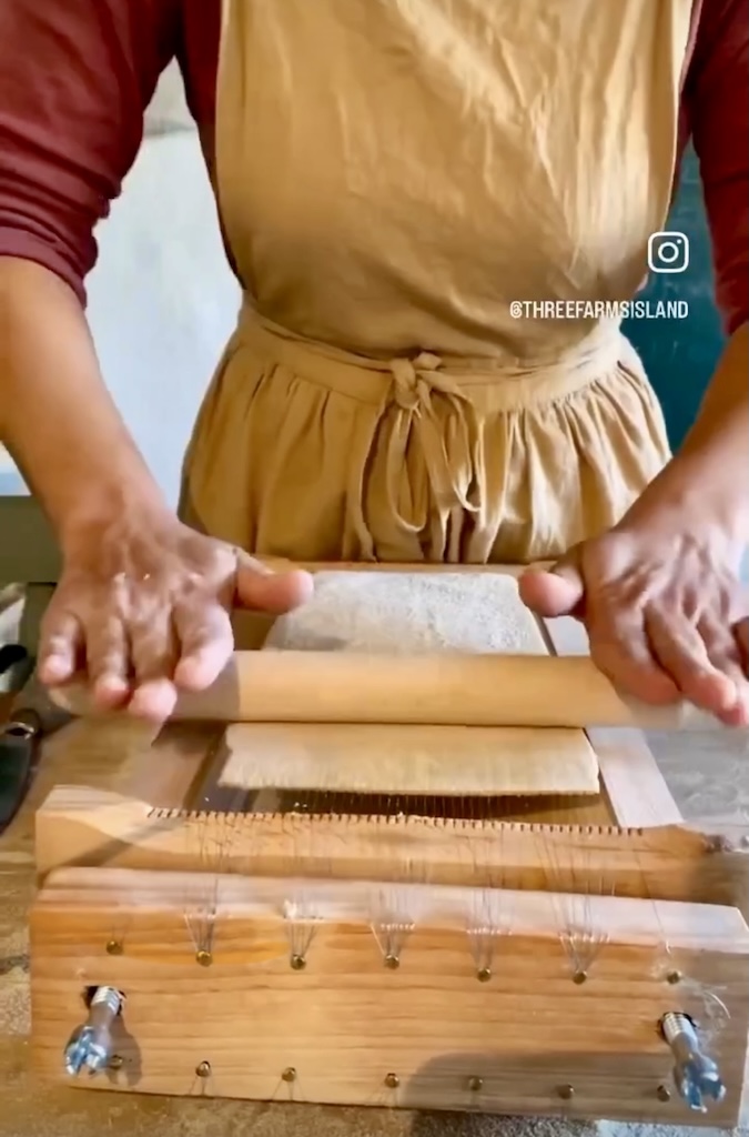 Pressing semolina dough through a traditional wooden chitarra to make fresh pasta — Three Farms Island, Sicily